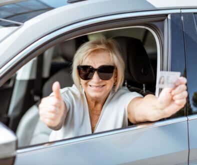 A woman who is giving the thumbs up sign after renewing her drivers license.