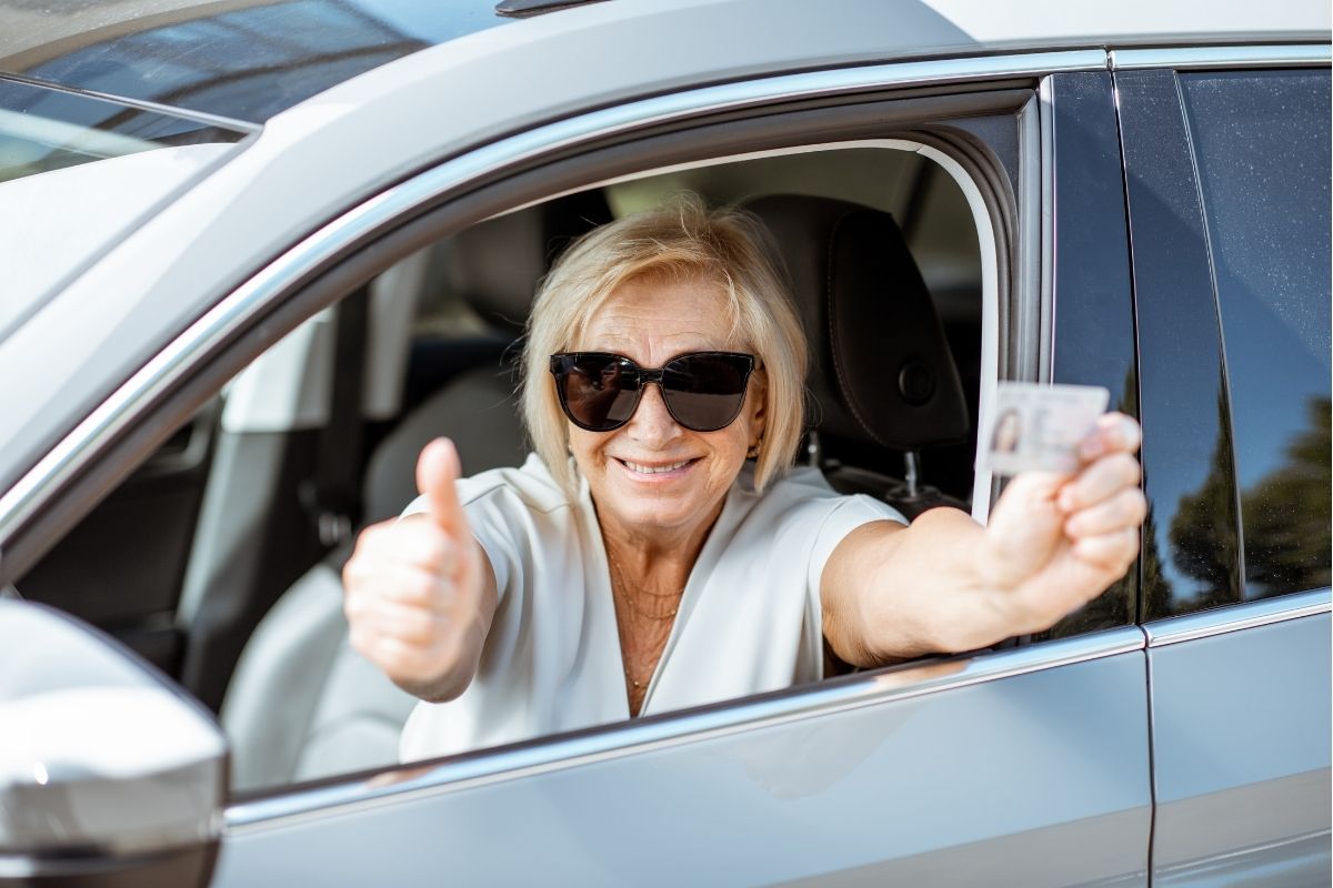 A woman who is giving the thumbs up sign after renewing her drivers license.