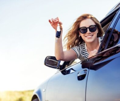 Happy woman wearing shades and showing her car keys in her window