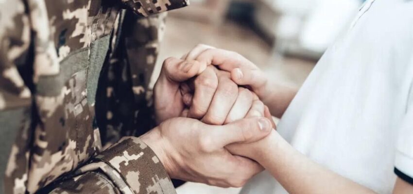 A military personnel holding hands with his wife.