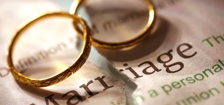 A pair of wedding rings on top of a marriage contract.