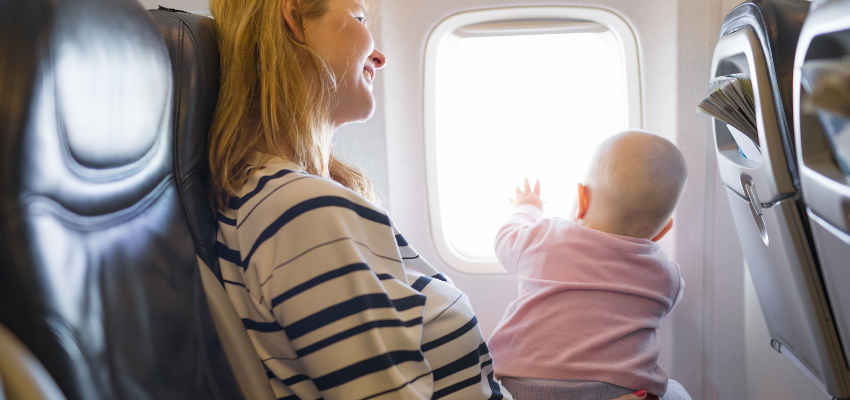 A mother holding a baby inside a plane.