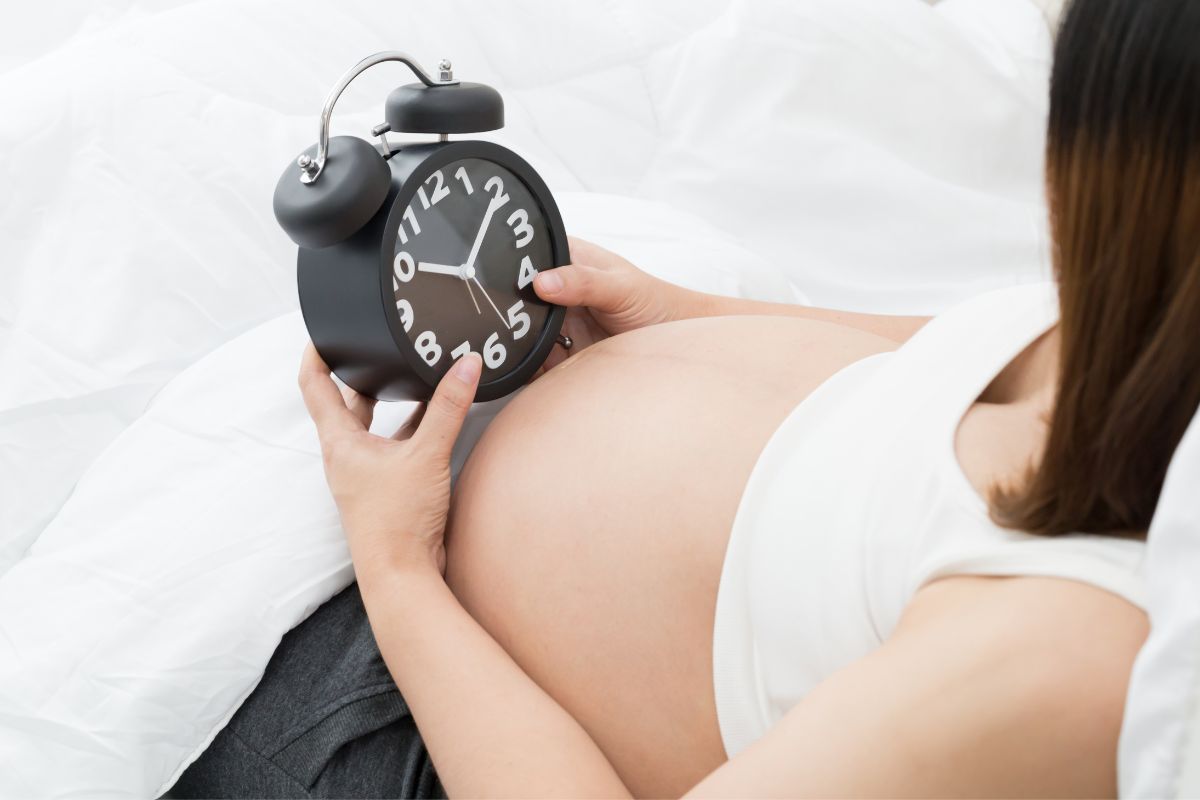 The pregnant woman checks the time and wonders when her first child will be born.